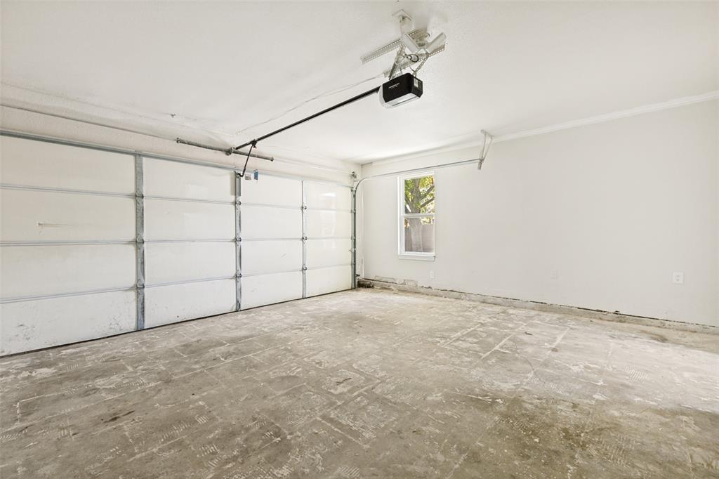 Spacious garage featuring a paneled overhead door, an automatic opener, a single window, and concrete flooring