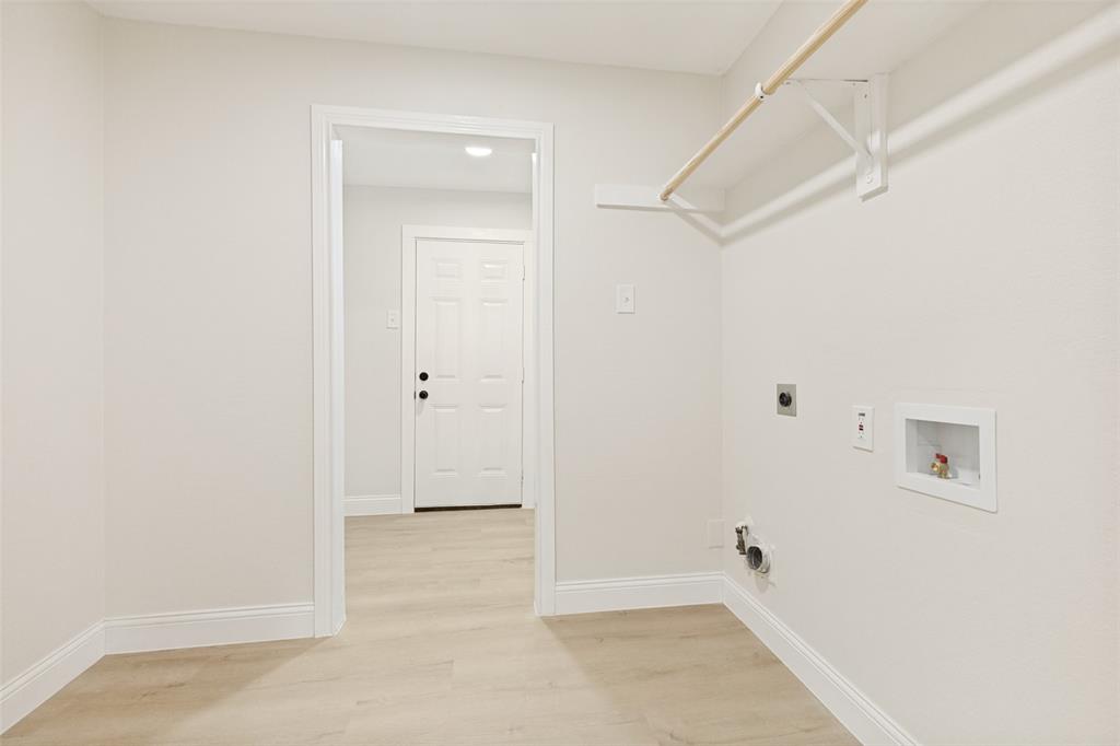 Dedicated laundry area featuring a light wood-finish flooring and a neutral color palette