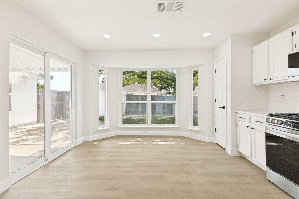 Bright interior space with light wood-finish flooring, recessed lighting, and a bay window