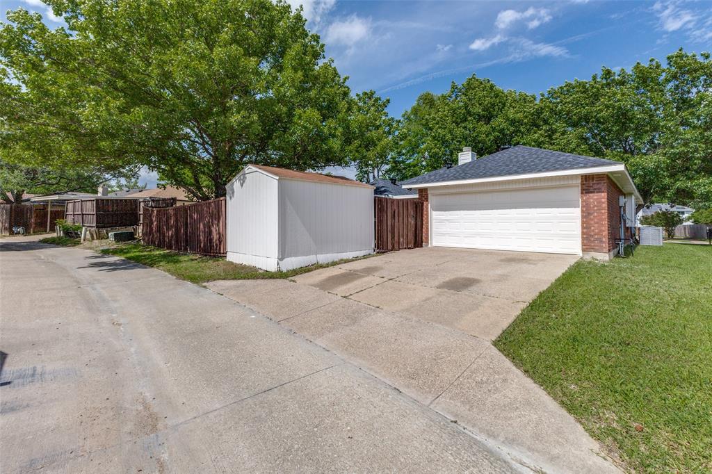 Brick exterior with a white garage door, dark shingle roof, and concrete driveway