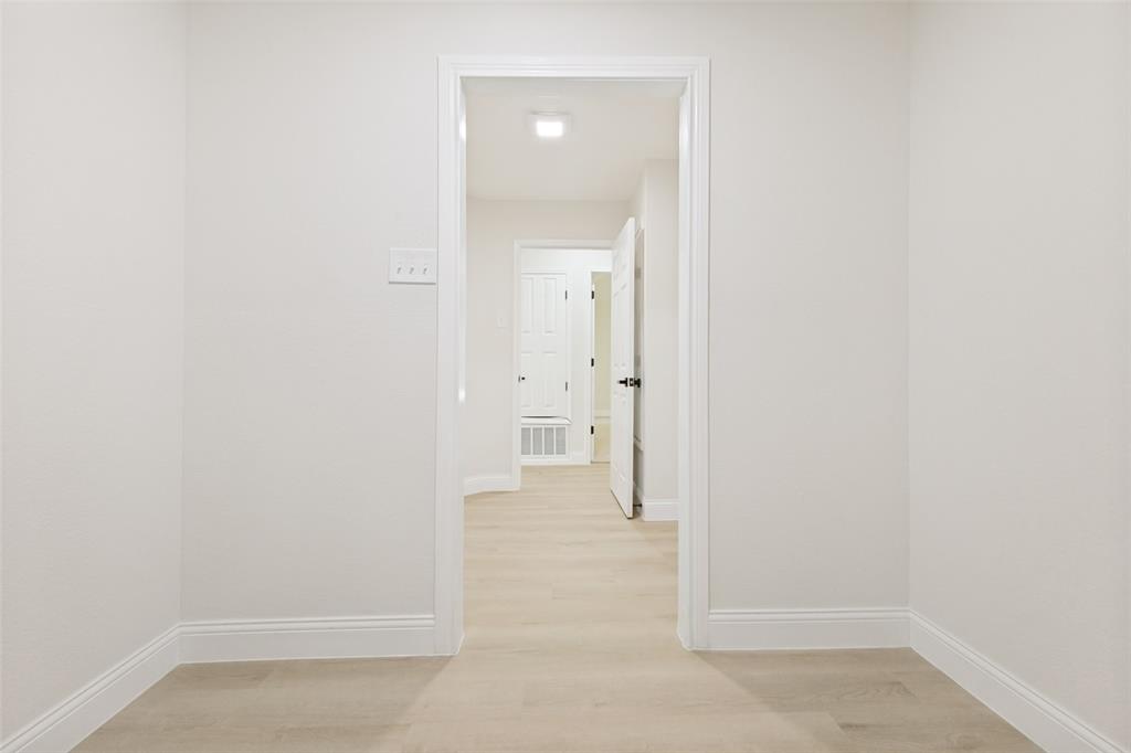 Hallway featuring light wood-finish flooring, white walls, and white baseboards