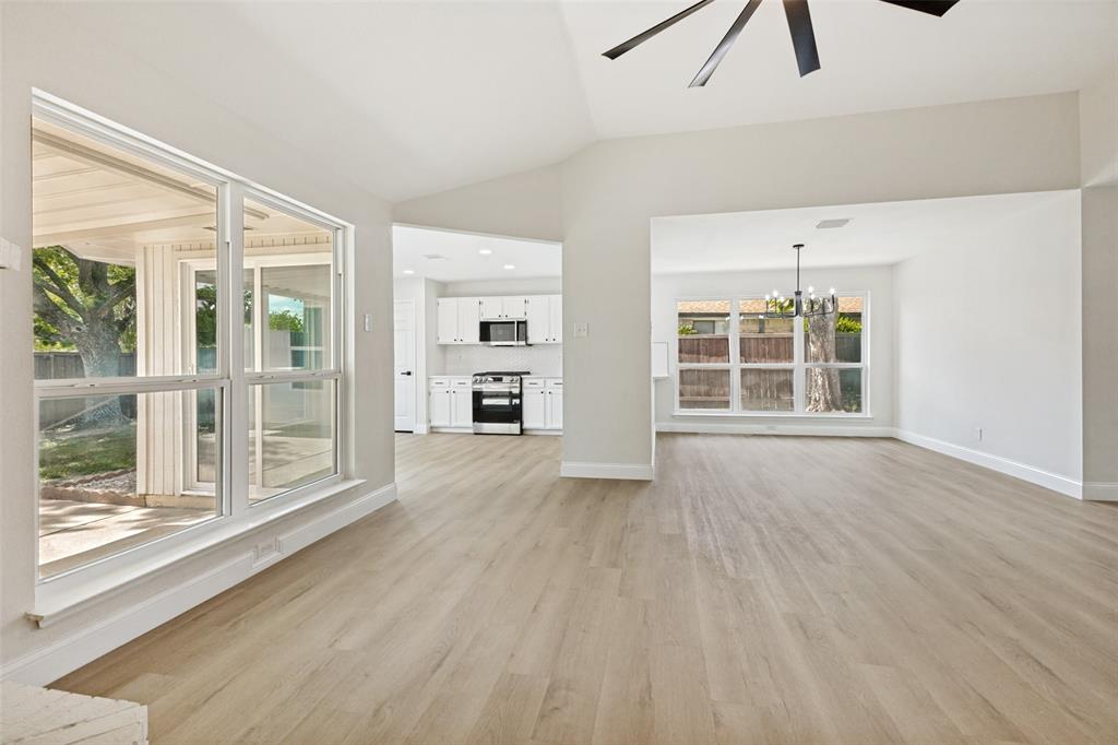 Vaulted ceiling living space featuring wood-finish flooring and a contemporary ceiling fan
