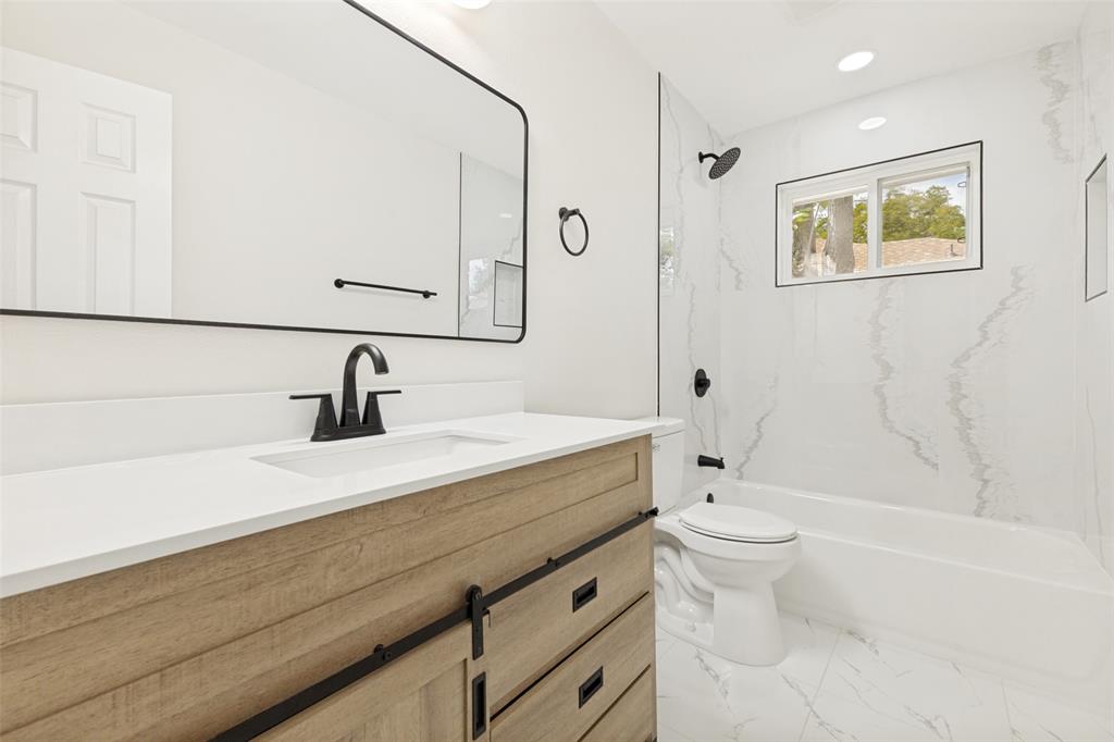 Bathroom featuring a wood-finish vanity with black hardware, white countertop, and a rectangular undermount sink