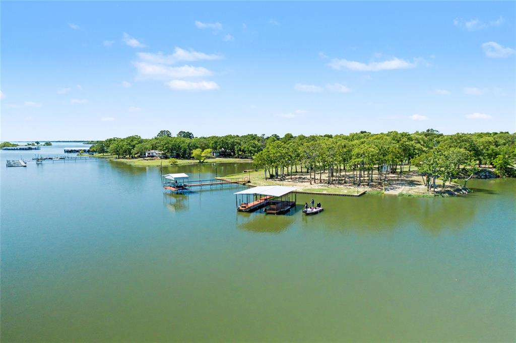 Waterfront property featuring multiple boat docks, a covered boat slip, and a forested shoreline