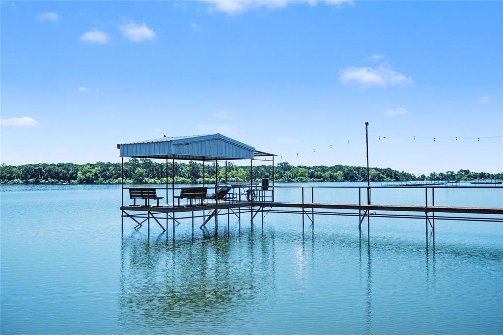 Private dock featuring a covered seating area with a metal roof, open-air walkway, and string lighting