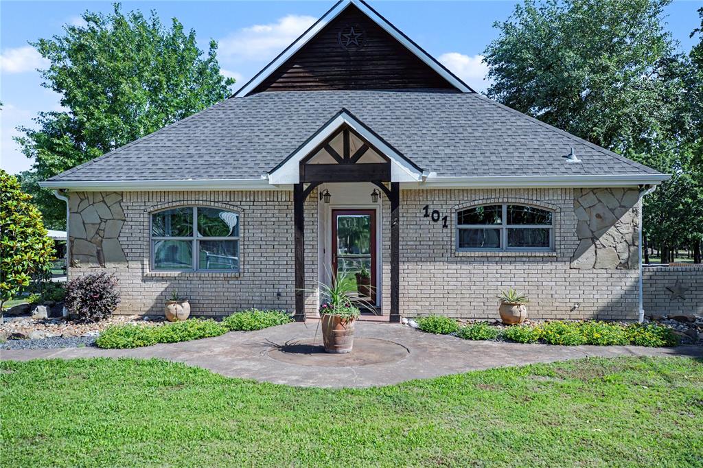 Exterior featuring light brick and stone accents, a gabled roofline with dark wood siding, and a covered entry with exposed timber beams
