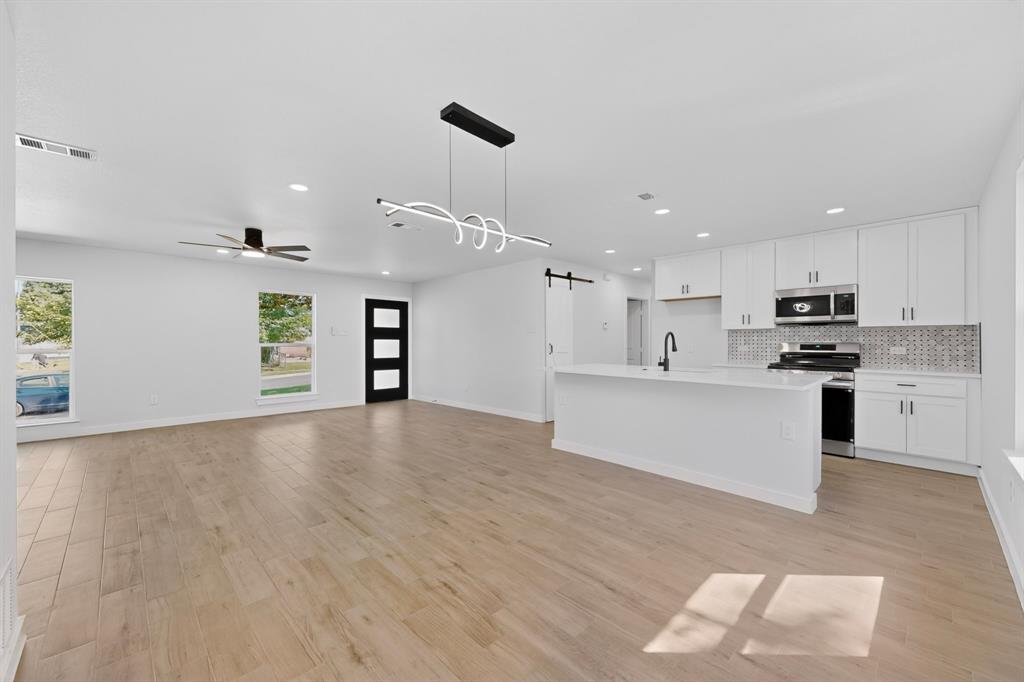 Spacious open-concept living area featuring wood-finish flooring and a contemporary linear light fixture