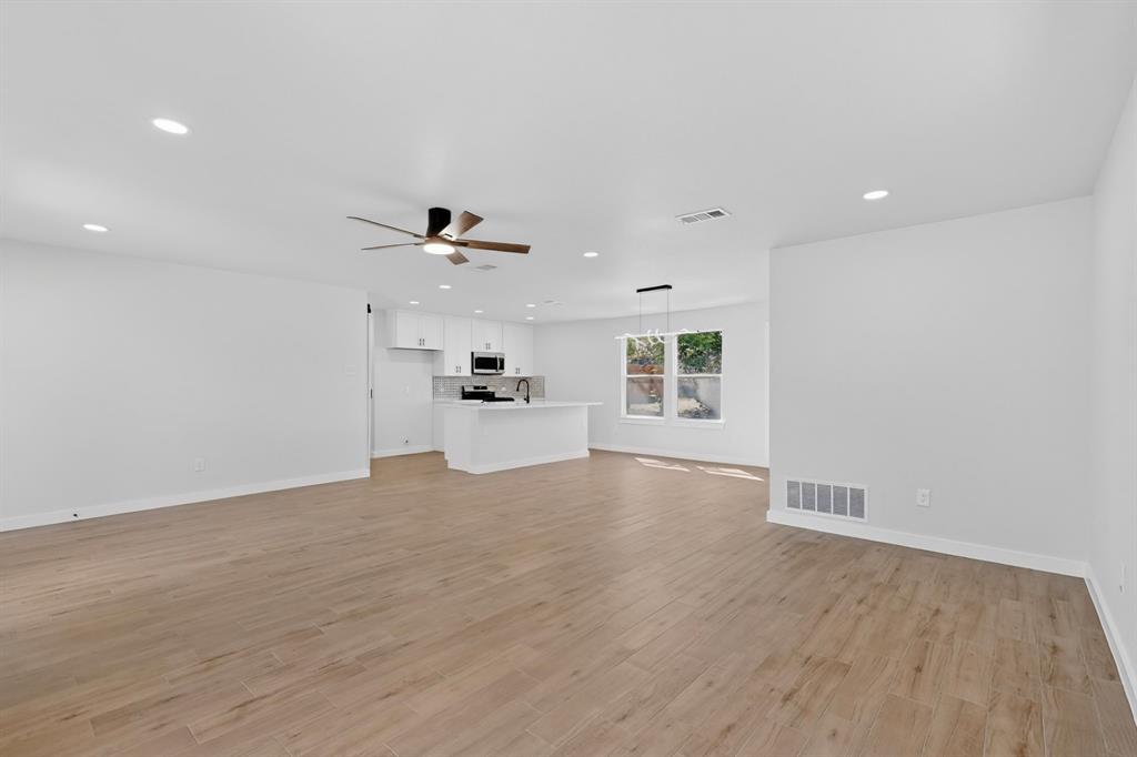 Expansive open-concept room featuring wood-finish flooring, recessed lighting, and a contemporary ceiling fan