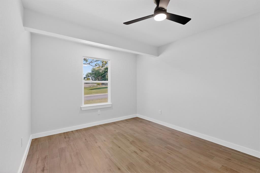 Bright interior space featuring wood-finish flooring, a contemporary ceiling fan with integrated lighting, and a window with white trim