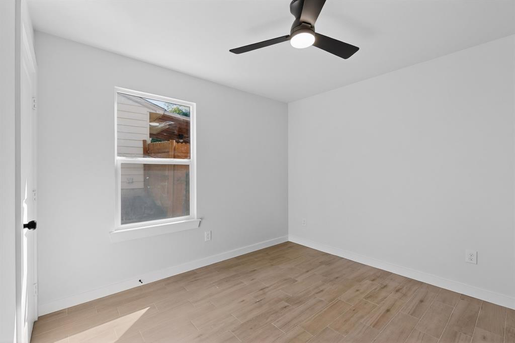 Room featuring light-toned wood-finish flooring, a contemporary ceiling fan with integrated lighting, a single window, and a white interior door with matte black hardware