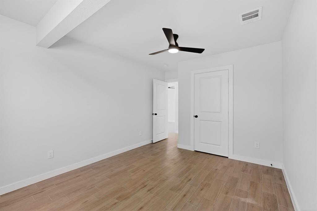 Bright room with wood-finish tile flooring, a modern black ceiling fan, white walls, and white paneled doors