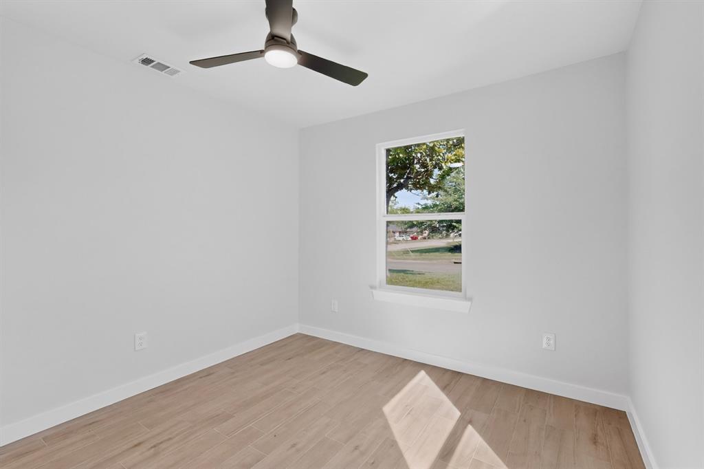 Light-filled room featuring wood-finish flooring and a contemporary ceiling fan