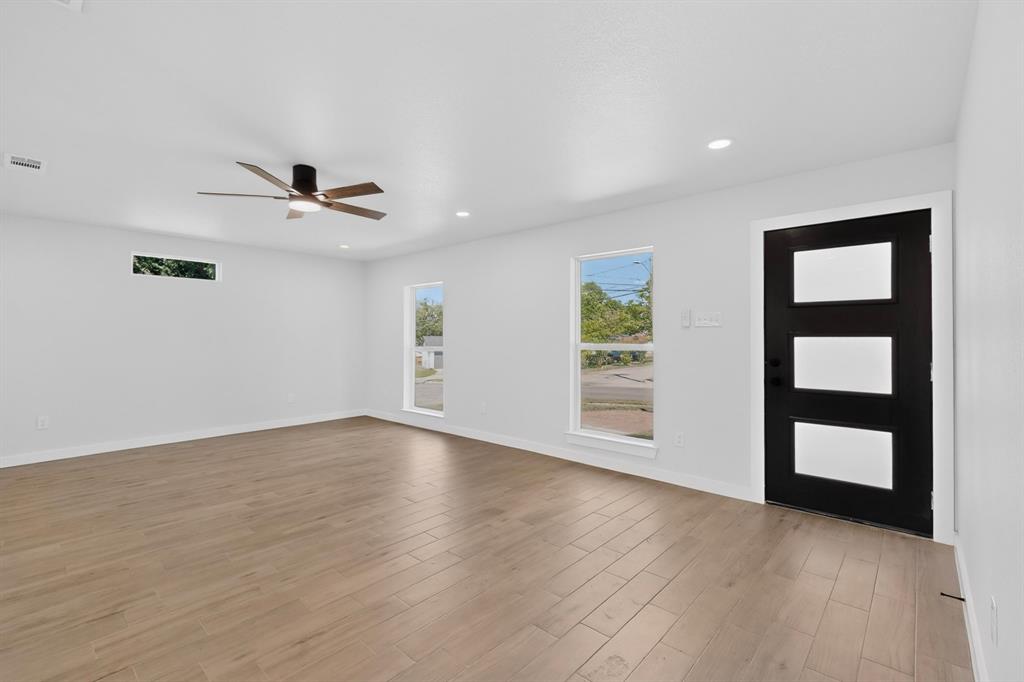 Spacious interior with wood-finish flooring, white walls, and recessed lighting