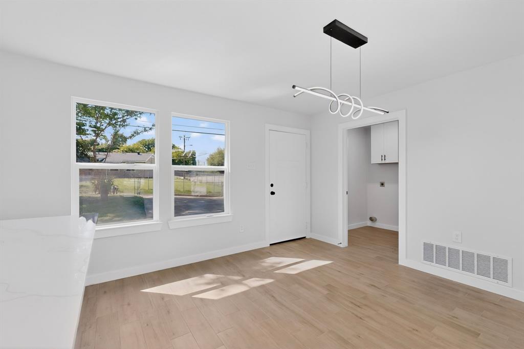 Open-concept room featuring wood-finish flooring, a modern linear chandelier, and a white interior door