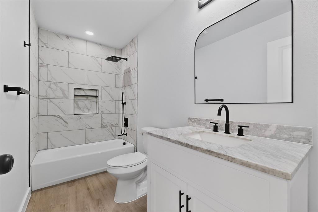 Bathroom featuring a white vanity with a stone countertop, an undermount sink, and matte black fixtures