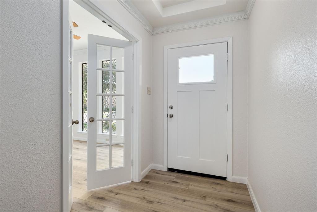 Entryway featuring light wood-finish flooring, a white front door with a square window, and decorative crown molding Entryway featuring light wood-finish flooring, a white front door with a square window, and decorative crown molding