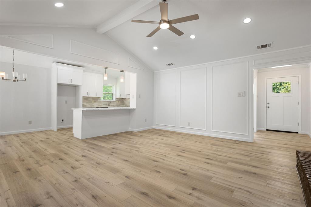 Open-concept living space with vaulted ceilings, wood-finish flooring, and recessed lighting