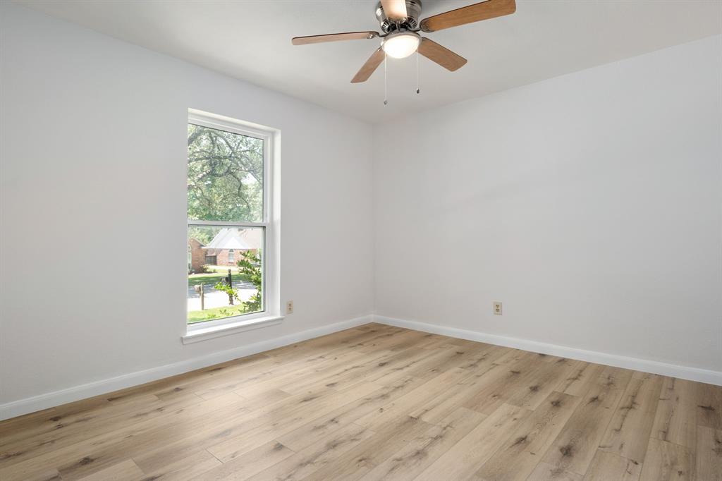 Interior room featuring light wood-finish flooring, white walls, and a ceiling fan with integrated lighting