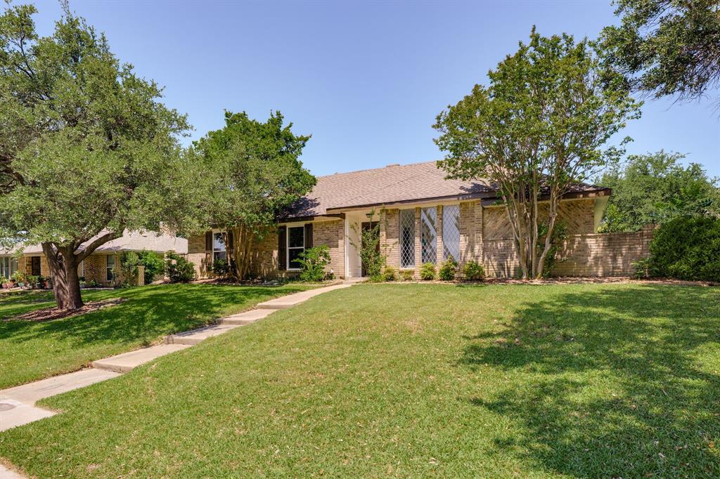 Brick facade residence featuring a front lawn with mature trees and a concrete pathway Brick facade residence featuring a front lawn with mature trees and a concrete pathway