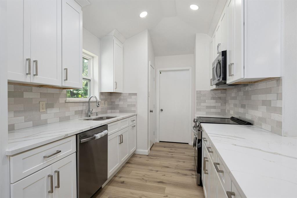Modern kitchen featuring white shaker cabinetry, quartz countertops, a subway tile backsplash, stainless steel appliances, and wood-finish flooring
