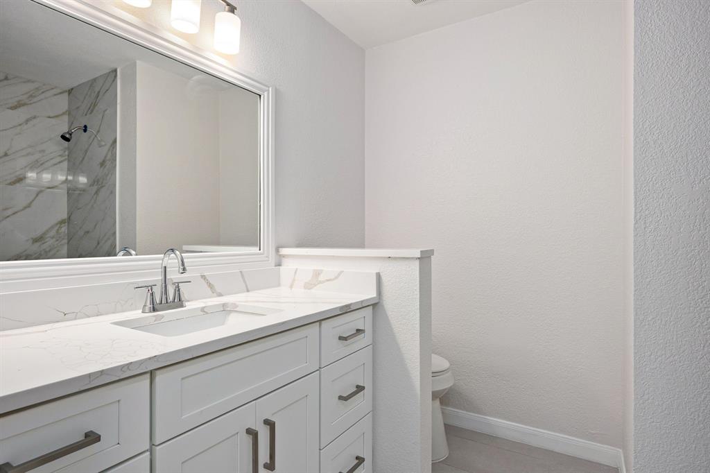 Bathroom vanity featuring a white countertop with integrated sink, brushed nickel faucet, and white cabinetry with coordinating hardware