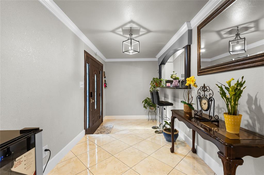 Entryway featuring a dark wood paneled door with sidelights, tile flooring, crown molding, and a contemporary ceiling fixture