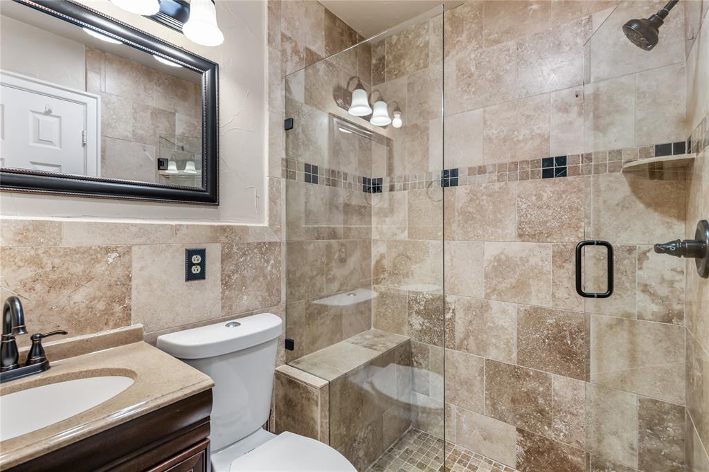 Walk-in shower featuring natural-toned tile, a built-in bench, and a glass enclosure