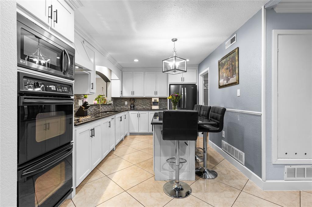 Kitchen featuring white cabinetry with dark hardware, dark countertops, a built-in double oven, and tiled flooring