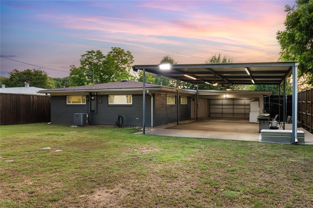 Expansive covered patio with integrated lighting and concrete flooring, featuring a detached garage with an overhead door