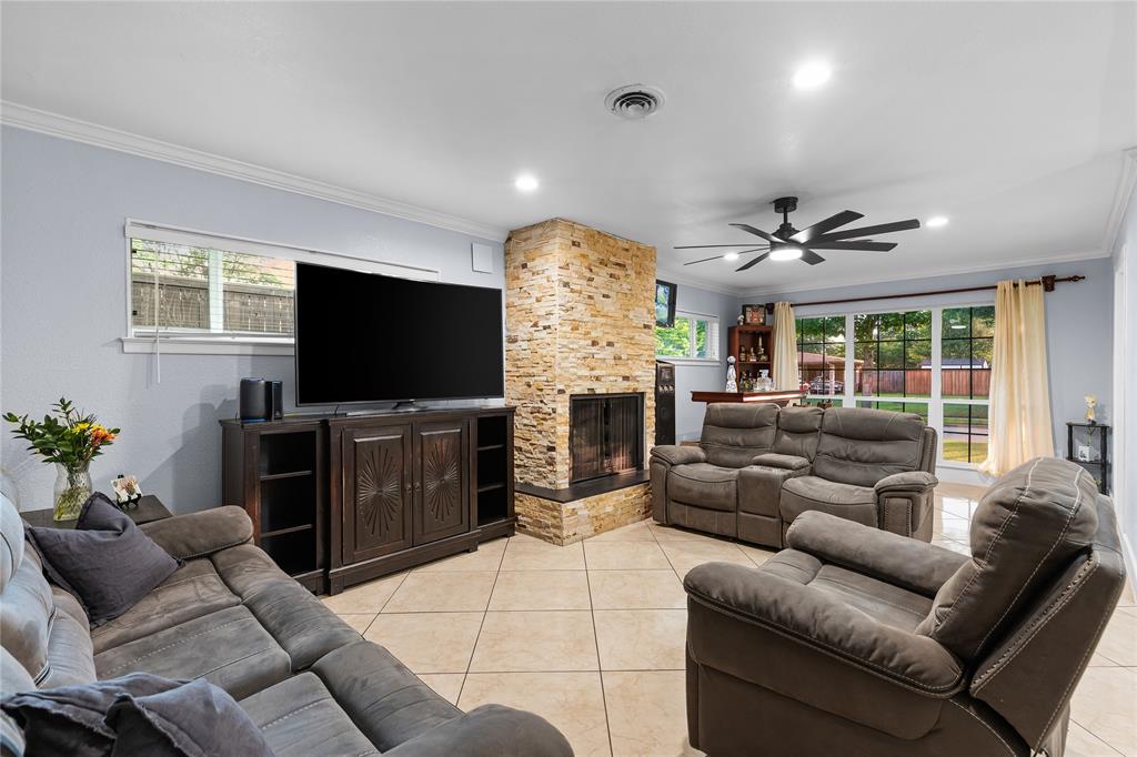 Living area featuring a floor-to-ceiling stacked stone fireplace, tile flooring, and multiple windows
