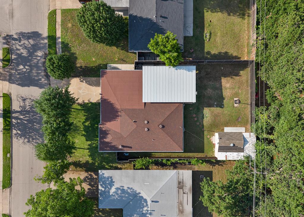 Aerial perspective of a property featuring a brown shingle roof and an attached white metal roof extension