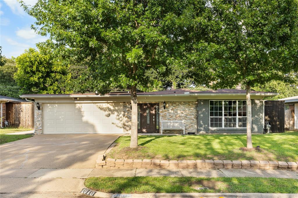 Single-story residence featuring a two-car garage, stone veneer facade, and a prominent front window with grid detailing