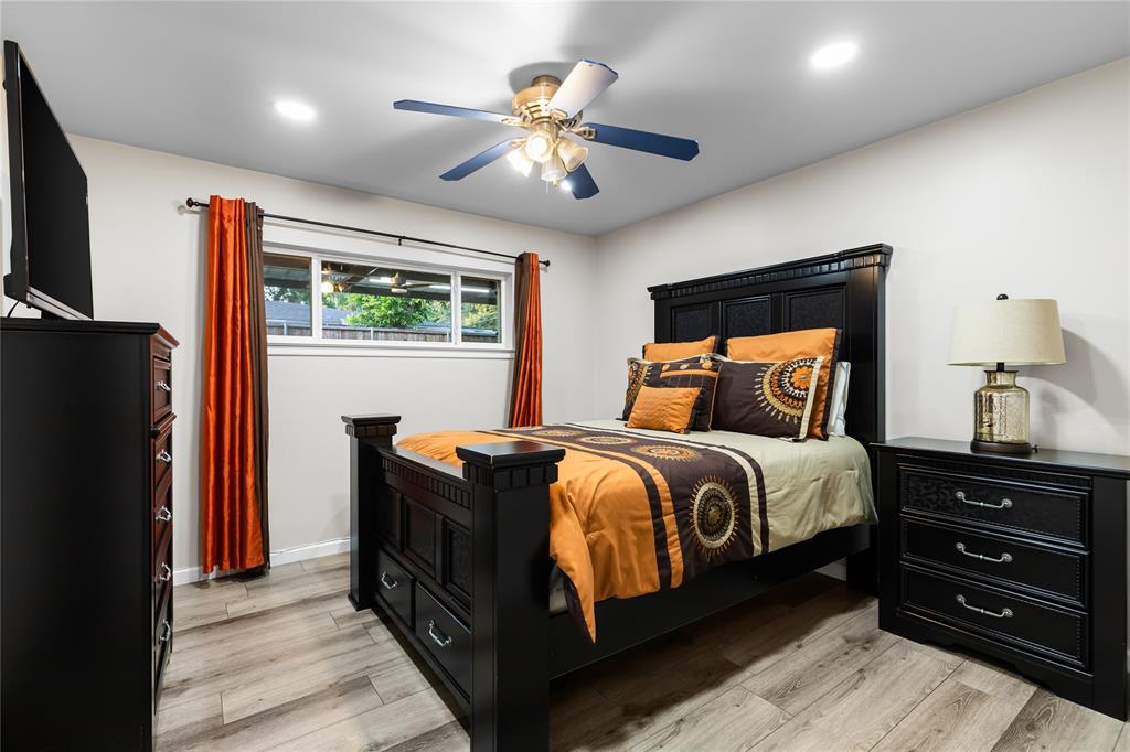 Spacious room featuring wood-finish flooring, a contemporary ceiling fan, recessed lighting, and a transom window with privacy glass