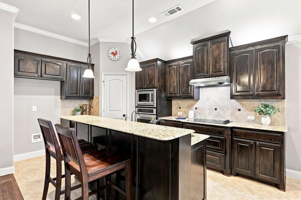 Kitchen featuring rich wood cabinetry, light-toned countertops, and a tile backsplash