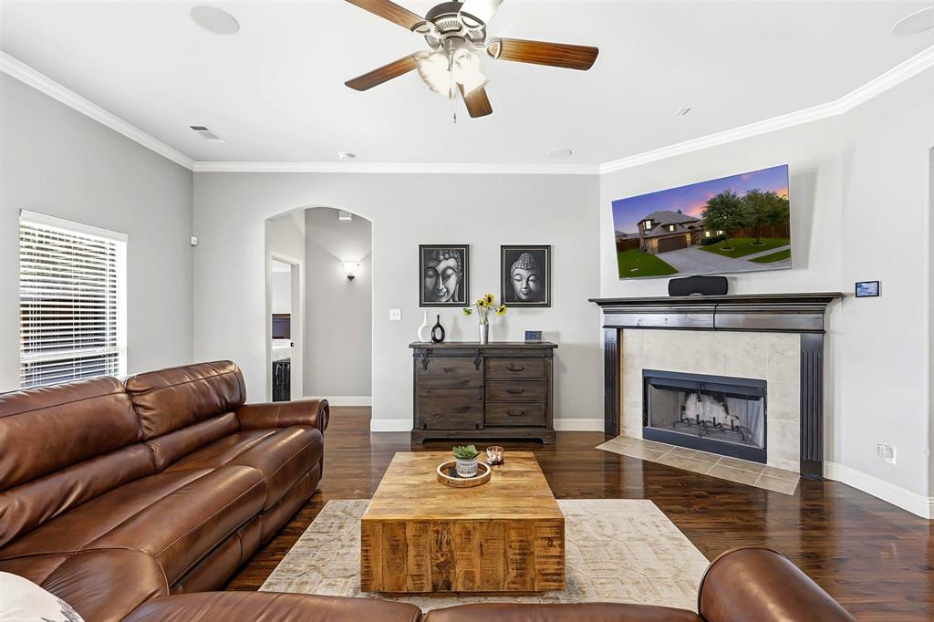 Living space featuring wood-finish flooring, a ceiling fan with light fixture, crown molding, and recessed lighting and wood burning fireplace.