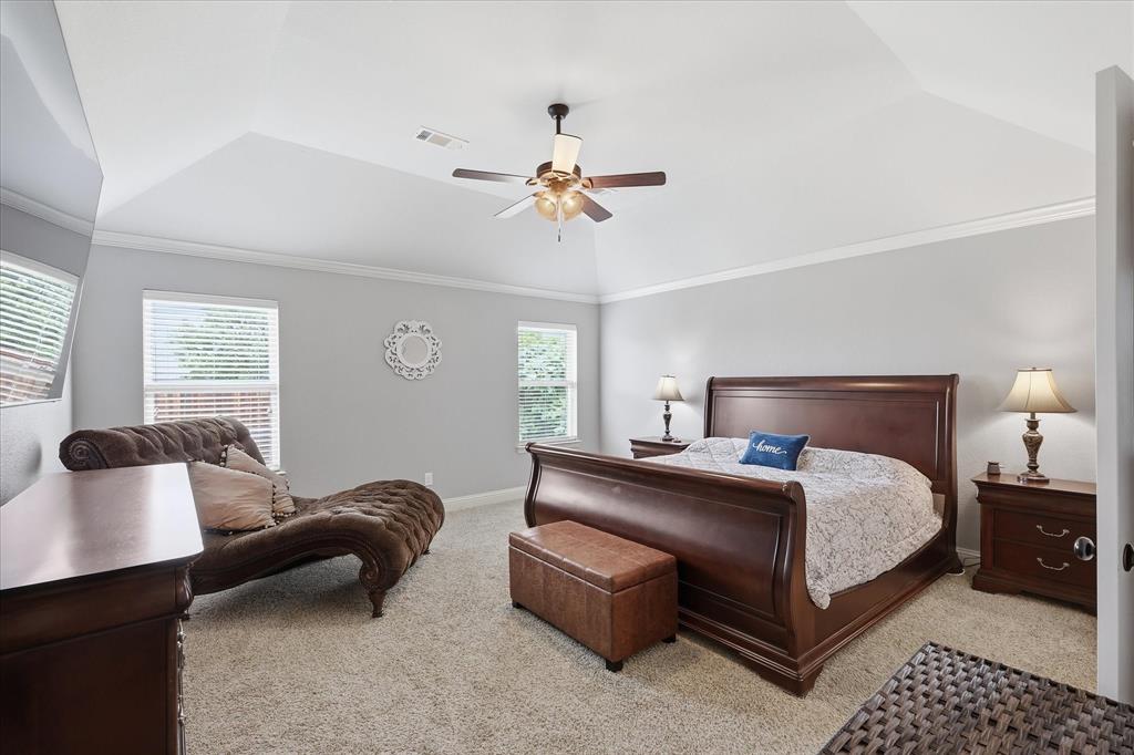 Carpeted interior space featuring a tray ceiling, crown molding, and a ceiling fan with light fixture