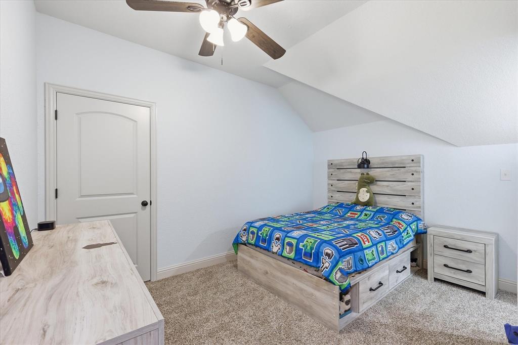 Spacious room featuring vaulted ceilings, a ceiling fan, light-toned carpeting, and a crisp white door with an arched panel design