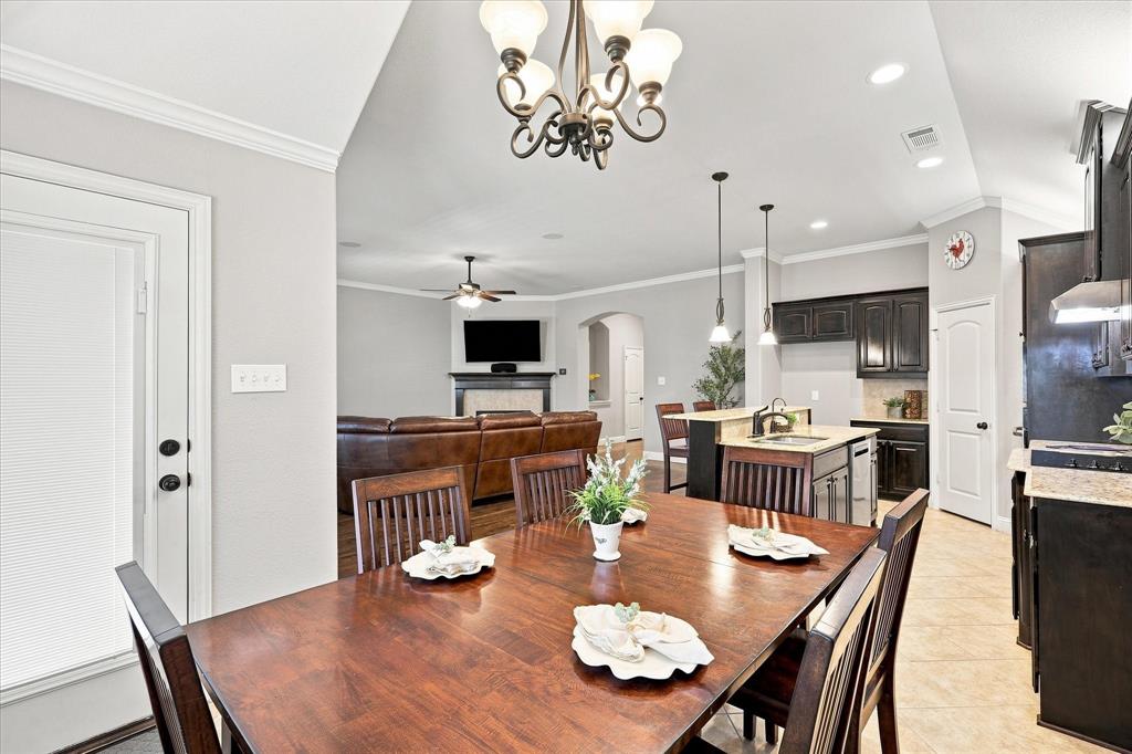 Open-concept layout featuring a kitchen island with sink, dark wood cabinetry, light-toned countertops, and tile flooring