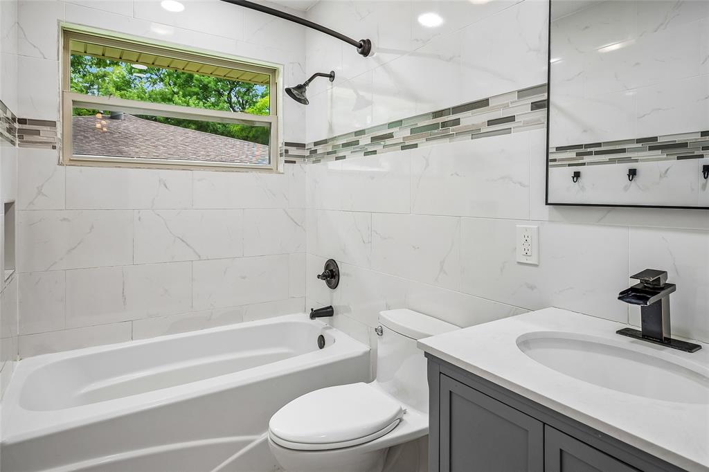 Modern bathroom featuring white tile walls with a decorative mosaic accent band