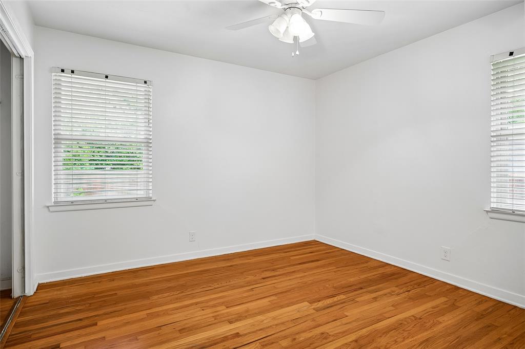 Hardwood flooring, white wall paneling, ceiling fan with light fixture, window with blinds, and white trim
