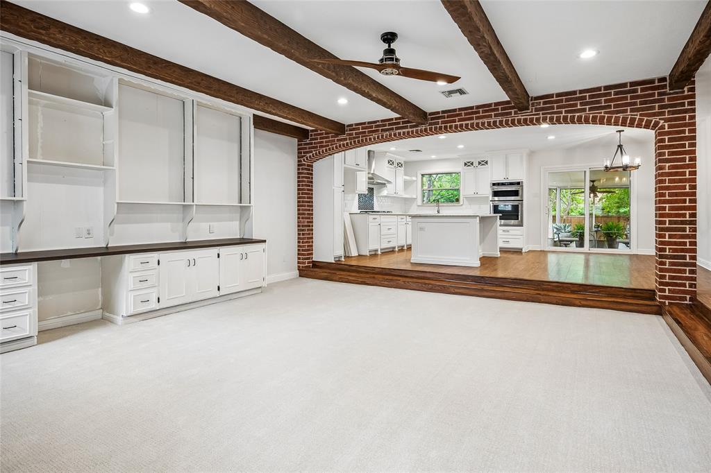Spacious room featuring exposed wood beams and recessed lighting