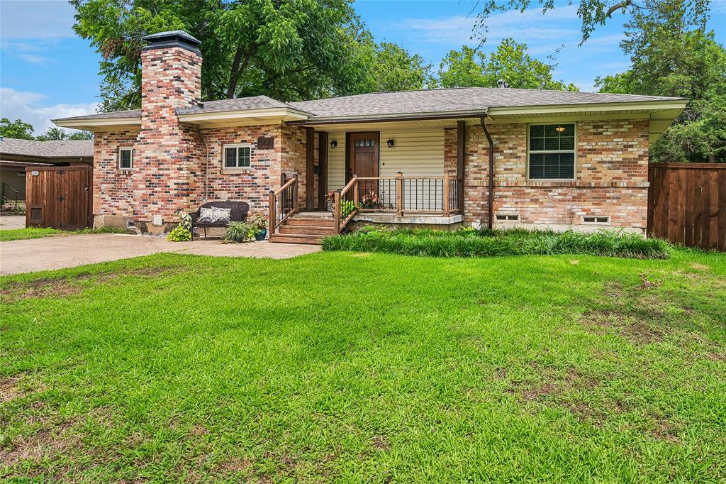 Brick-clad exterior with a prominent chimney, inviting front porch, and a well-kept lawn