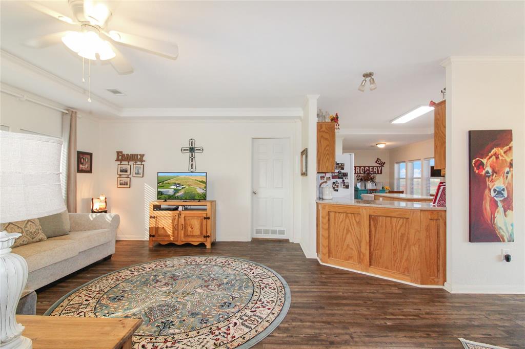 Expansive open-concept living area featuring wood-finish flooring, a tray ceiling, and a ceiling fan