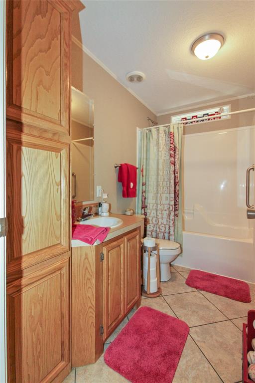 Bathroom featuring a built-in wood-finish cabinetry, a single vanity with an integrated sink, a commode, and a tub/shower combination