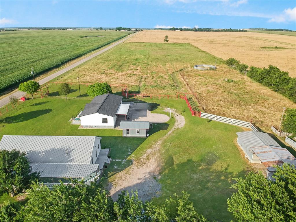 Expansive property featuring multiple structures, including a primary residence with a dark shingle roof and a separate metal-roofed building Expansive property featuring multiple structures, including a primary residence with a dark shingle roof and a separate metal-roofed building