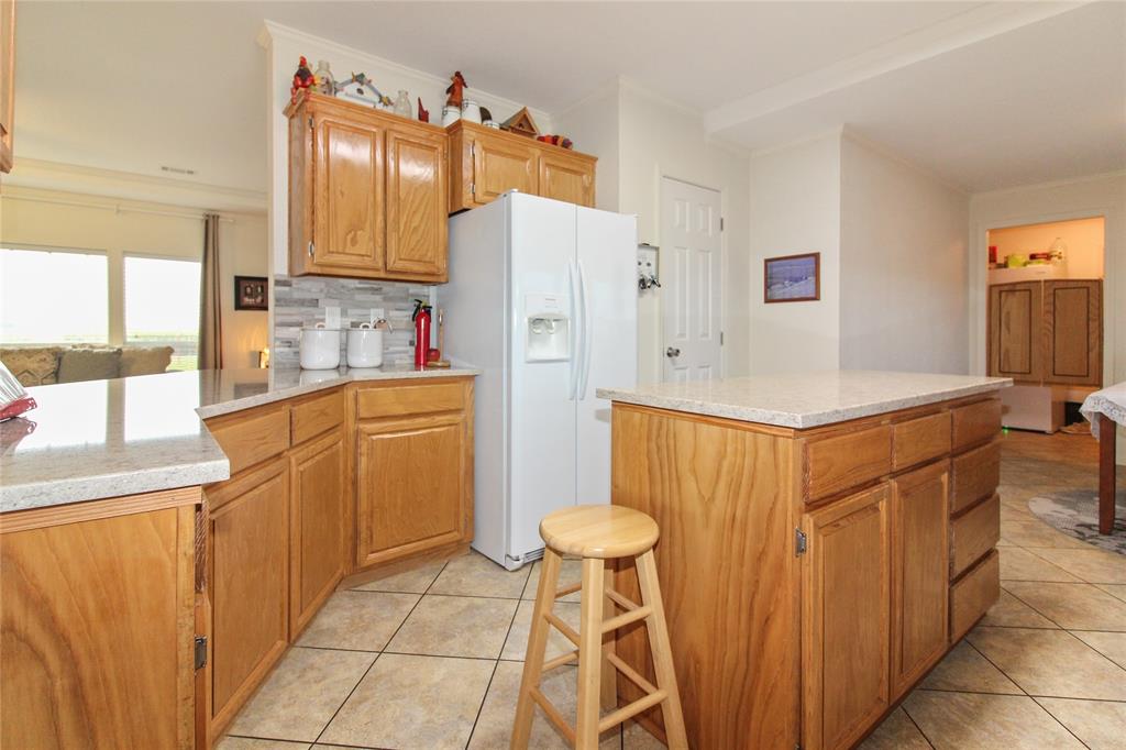 Kitchen featuring wood cabinetry, stone-look countertops, a tile backsplash, and tile flooring