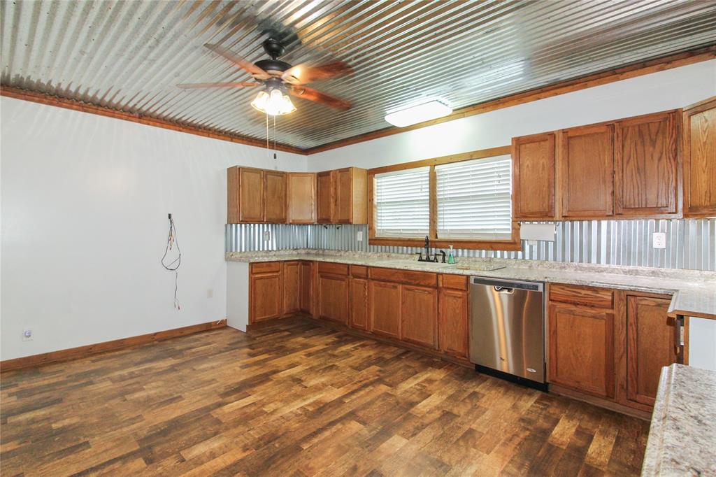 1936  HOUSE Kitchen featuring a corrugated metal ceiling, wood-finish flooring, wood cabinetry, stone-look countertops, and a stainless steel dishwasher