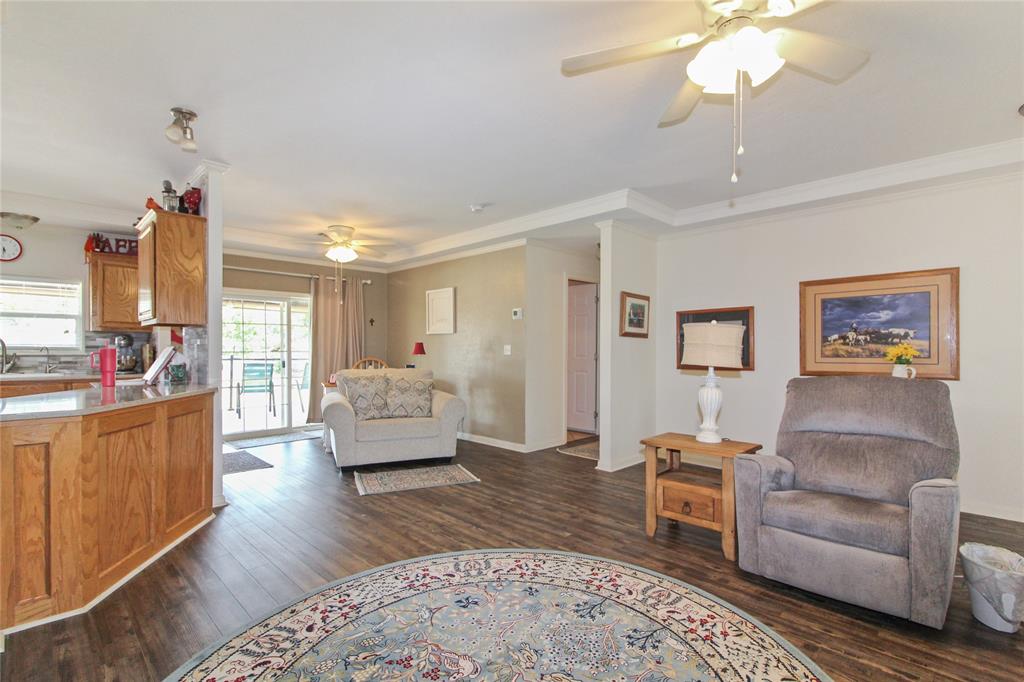 Spacious living area featuring wood-finish flooring, crown molding, and multiple ceiling fans