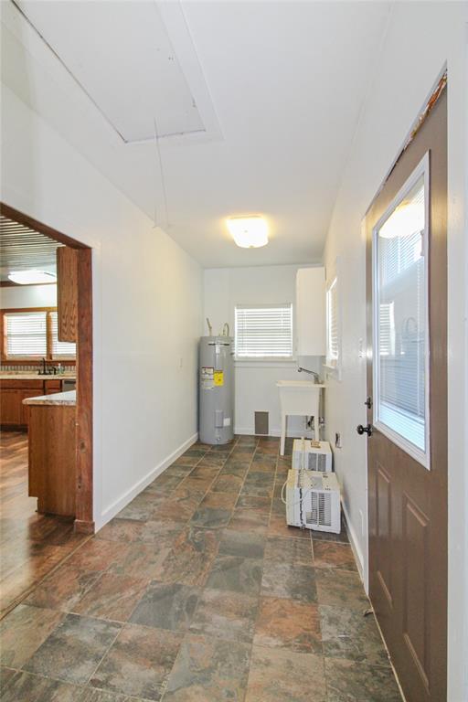 1936  HOUSE Utility area featuring a water heater, utility sink, and tiled flooring