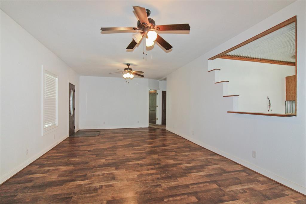 1936  HOUSE Spacious living area featuring wood-finish flooring, two ceiling fans with integrated lighting, and a white interior paint scheme